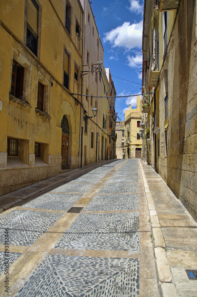 Deserted street of old European town on a clear Sunny day. The bright walls of the old town of Tarragona in Catalonia.