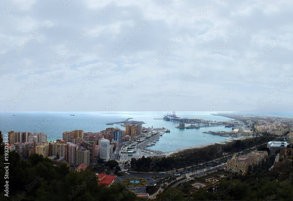 panoramic aerial image of malaga in spain showing the coast with port and docks with surrounding city hotels and ships out at sea