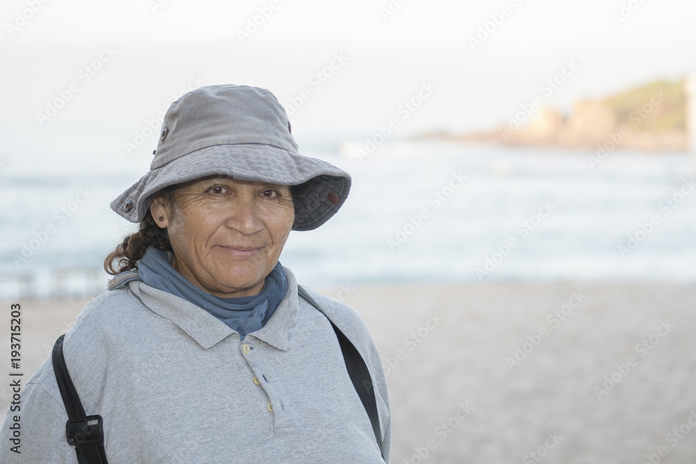 Older Smiling & Friendly Mexican Woman Working on a Resort Beach Raking and Cleaning up the Sand