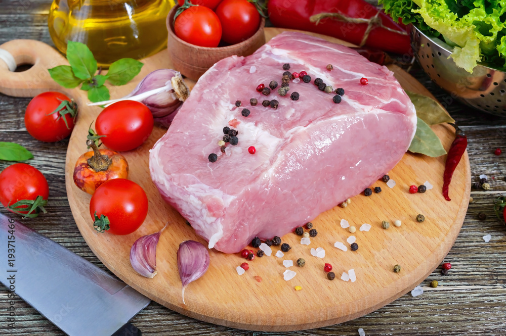 Raw meat. A large piece of pork with spices and salt on a cutting board on a wooden table. Raw meat. A large piece of pork with spices and salt on a cutting board on a wooden table.