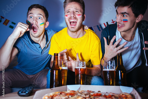 Soccer or football fans watching the match at home, cheering and celebrating goal photo