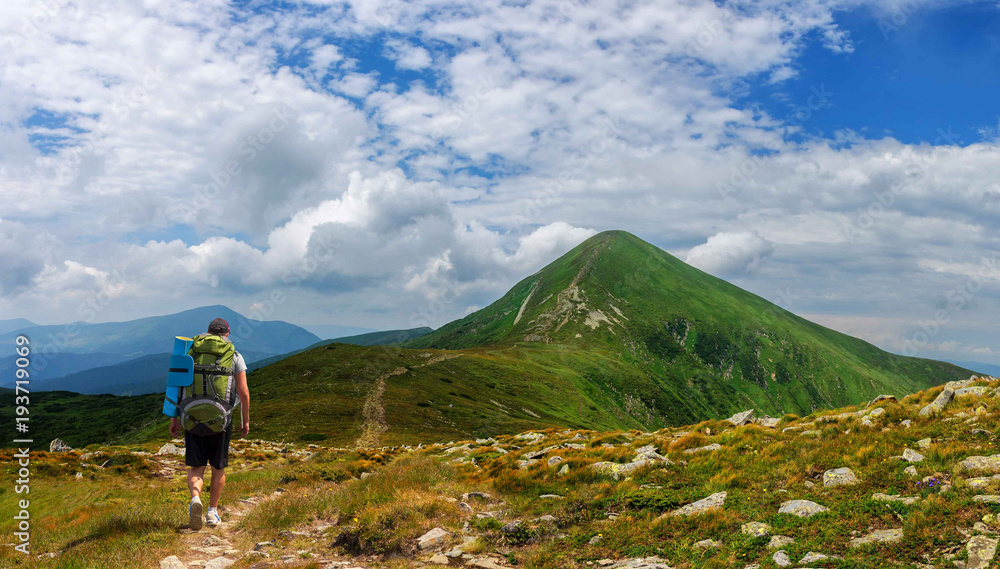 A tourist with a large backpack rises to Goverla mountain in Carpathian mountains Ukraine