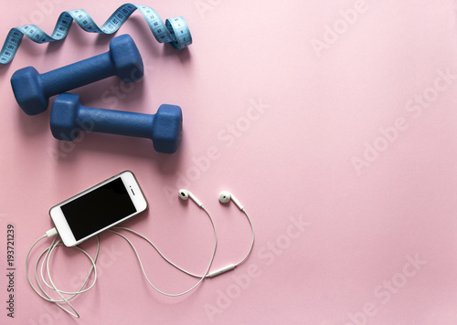 on a pink background dumbbells blue and flying centimeter figure sport headphones music phone smartphone soft light 