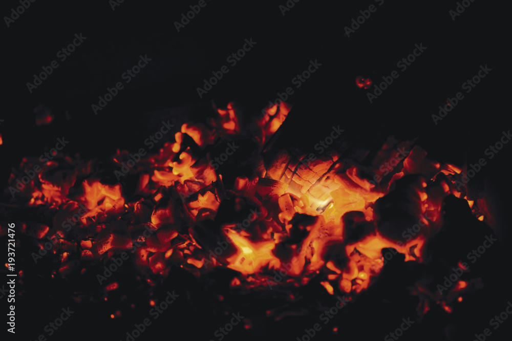 Fototapeta premium Hot red coals from firewood in a fireplace on a black background