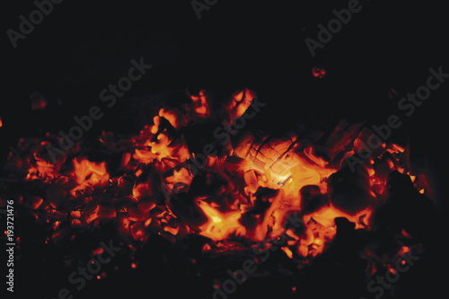 Hot red coals from firewood in a fireplace on a black background