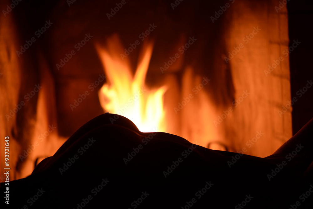 silhouette of a woman's breast against the background of a burning fire in the fireplace silhouette of a woman's breast against the background of a burning fire in the fireplace