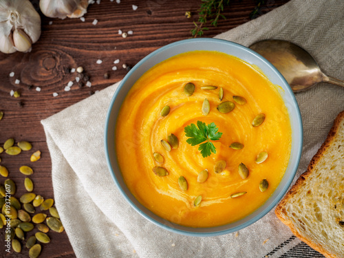 Dietary vegetarian pupmkin cream soup puree,  on dark brown wooden table, top view, close up. photo