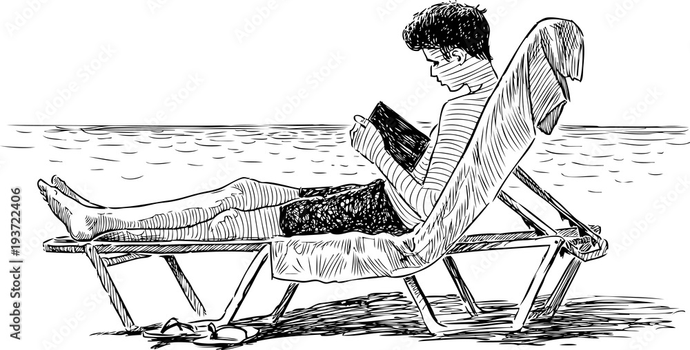 Fototapeta premium A teen boy reads a book on a beach