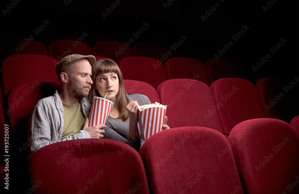 Naklejka premium Young couple sitting at red movie theatre