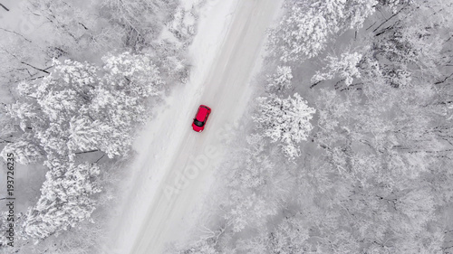 red car driving on a snow covered road, aerial view