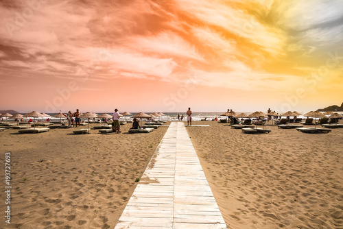 Fototapeta Naklejka Na Ścianę i Meble -  Iztuzu beach, Turkey - May 10, 2017: Sandy beach and tourists stare at the sea and colorful sky on Iztuzu beach. Editorial photo