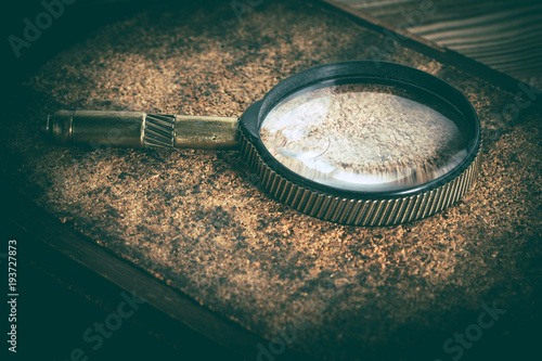 Old magnifying glass or loupe on cork background.