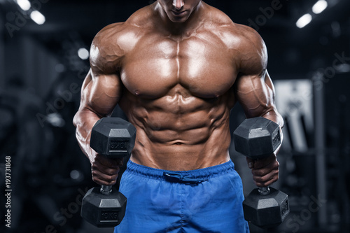 Fototapeta Mięśniowy mężczyzna pracujący w gym robi ćwiczeniom z dumbbells, silny męski nagi półpostać abs