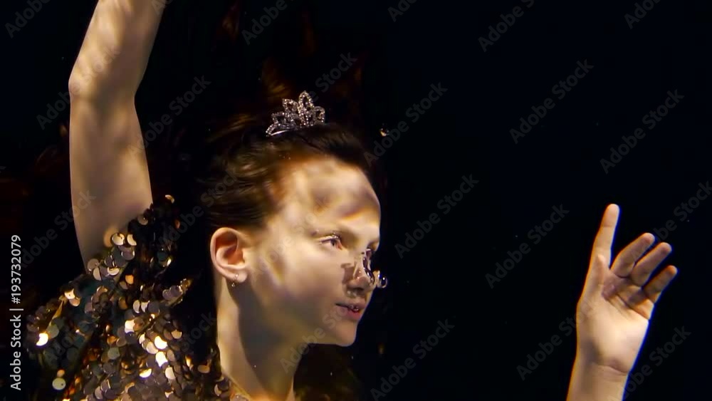cute teenager is under water with a tiara on her head, a girl is swimming in the sea cute teenager is under water with a tiara on her head, a girl is swimming in the sea