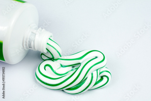 Green and white toothpaste squeezed out of a tube dental hygiene concept, close up, selective focus, white background