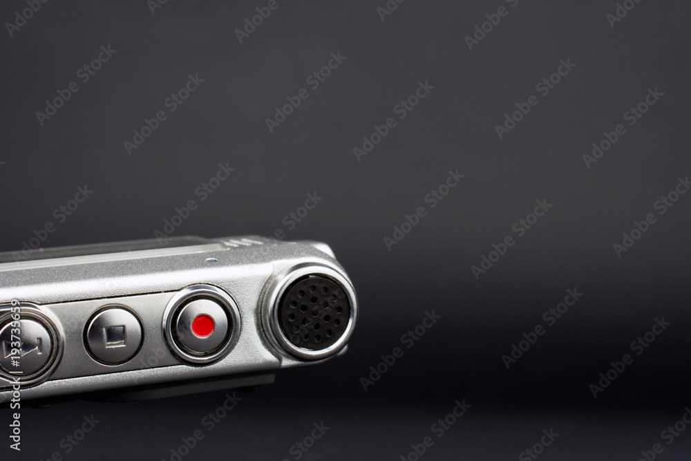 Fototapeta premium dictaphone closeup of a red record button selective focus dark blurred background journalism concept copy space