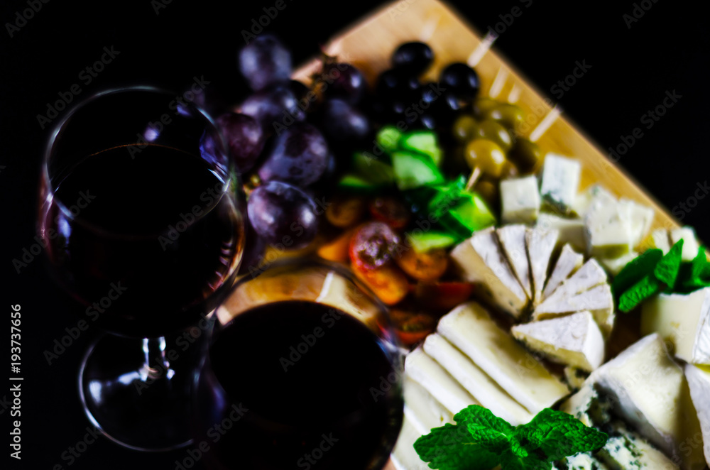 Red wine and set of different cheeses on a wooden board, delicious snack Red wine and set of different cheeses on a wooden board, delicious snack
