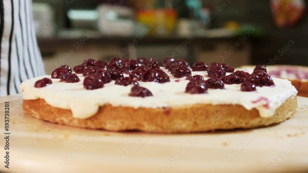 Woman decorate homemade cake with a cherry on sponge cake Woman decorate homemade cake with a cherry on sponge cake