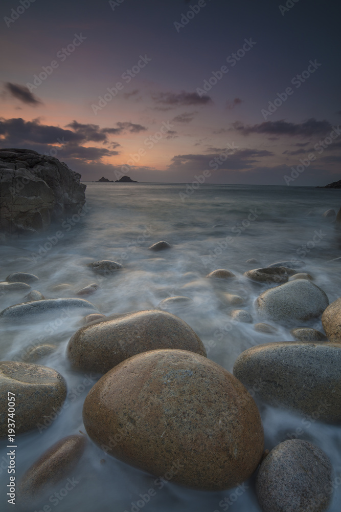 Boulders on Porth Nanven beach looking towards the Brisons at sunset Cot Valley near St Just Cornwall