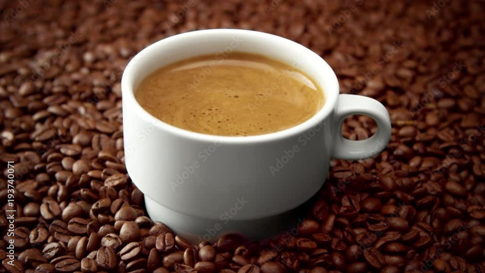 side view of white cup of black coffe on coffee beans. Hand put a cup on coffee beans side view of white cup of black coffe on coffee beans. Hand put a cup on coffee beans
