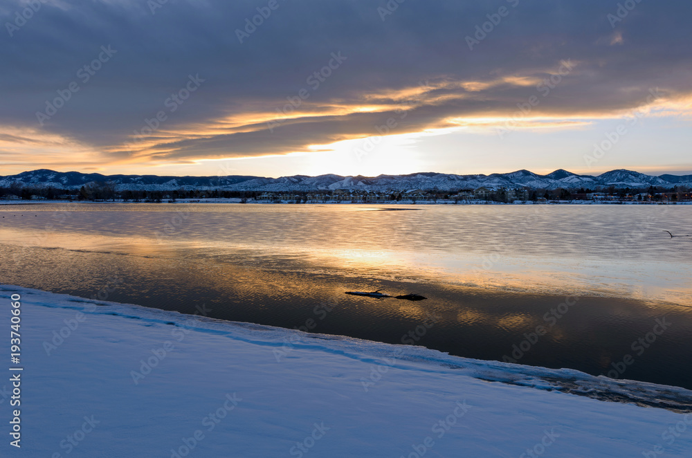 Stormy Winter Lake - A sunset view of winter storm clouds hanging over a snow and ice covered mountain city lake.