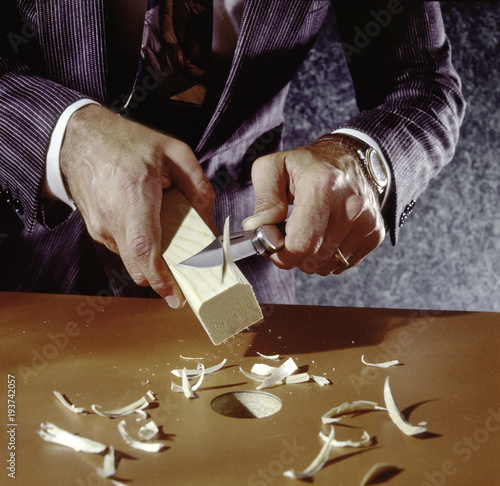 man carving square peg to fit round hole wearing suit photo