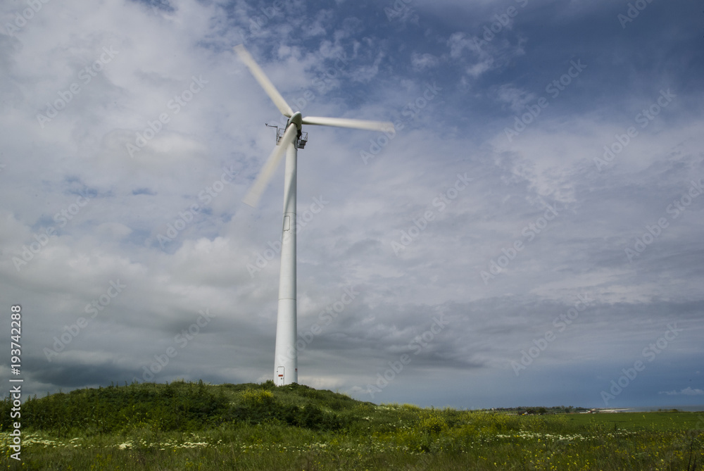 Windmill with motion blur propeller/Windmill seen while rotating on a field in Romania where the winds are favorable for renewable energy.