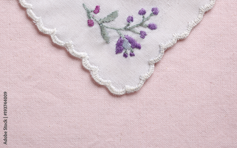 Textile with embroidered flower on pink background