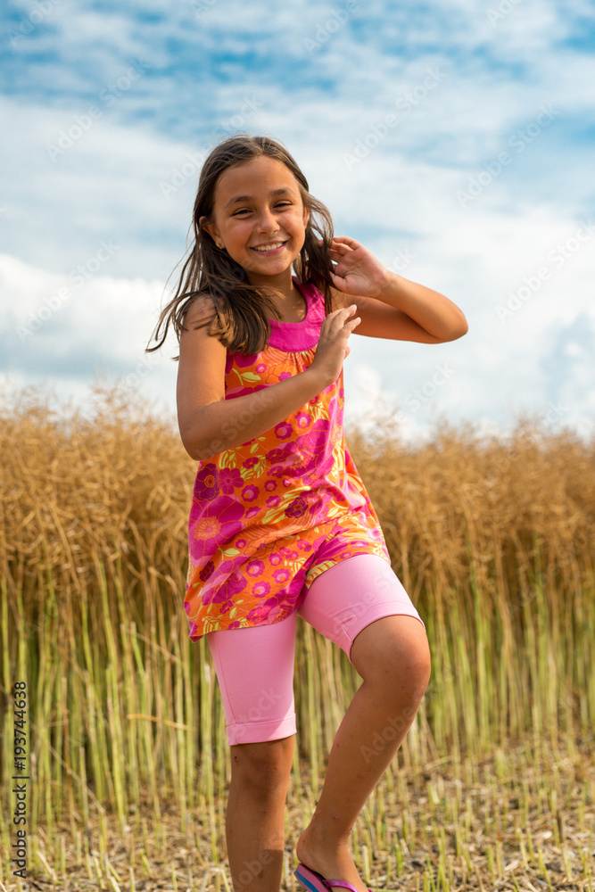 Happy little girl in a field of ripe rapeseed - vertical orientation Happy little girl in a field of ripe rapeseed - vertical orientation