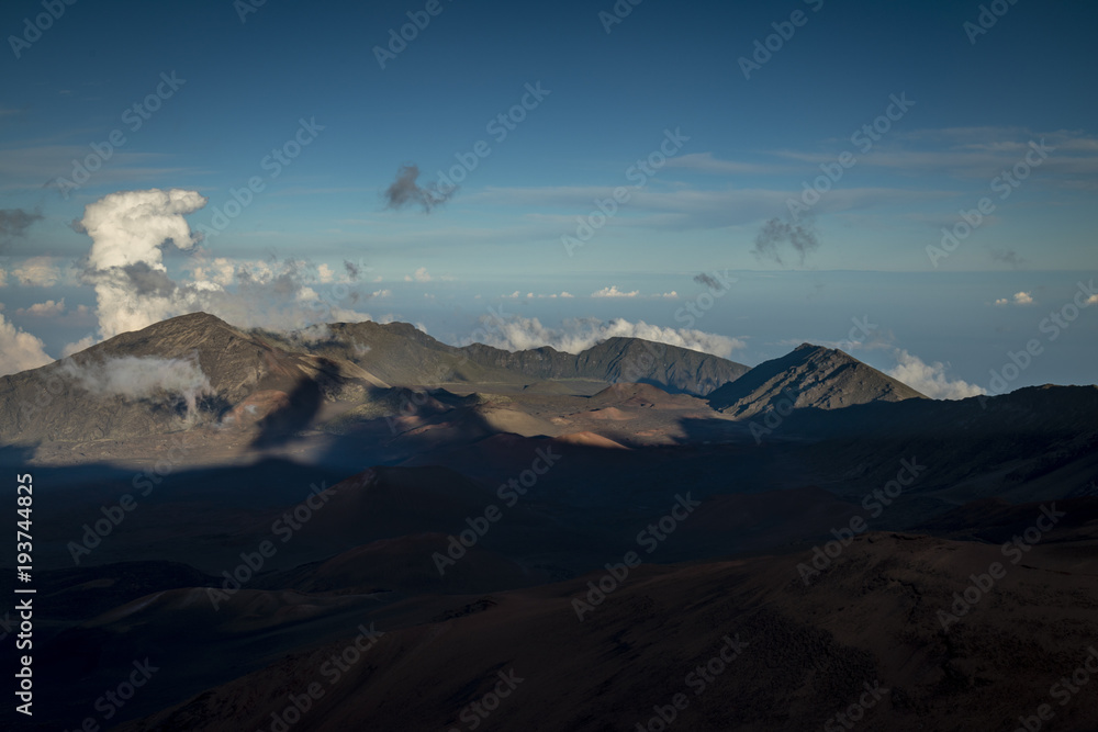 view taken from a high altitude at the summit of haleakala on the island of maui in hawaii in the pacific ocean showing the view down into the haleakala crater with shadows moving and clouds
