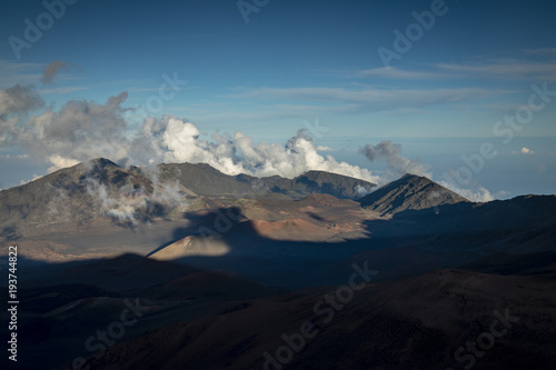view taken from a high altitude at the summit of haleakala on the island of maui in hawaii in the pacific ocean showing the view down into the haleakala crater with shadows moving and clouds