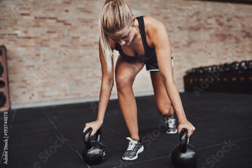 Focused young woman working out with weights in a gym