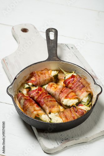 Vegetables and bacon meat roasted in pan. White wooden background, natural light