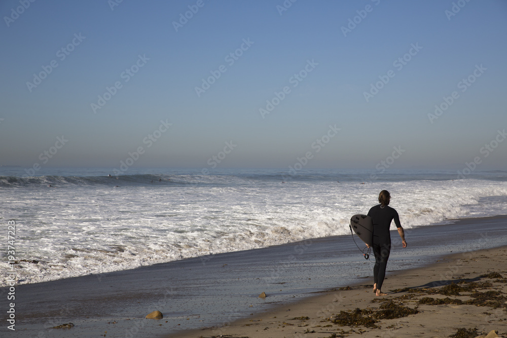 A man carries a surfboard as he walks along the beach A man carries a surfboard as he walks along the beach