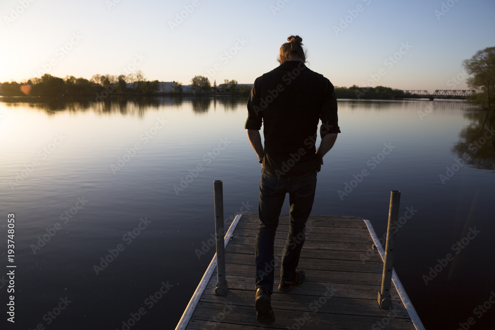 Man walks on a dock over still water