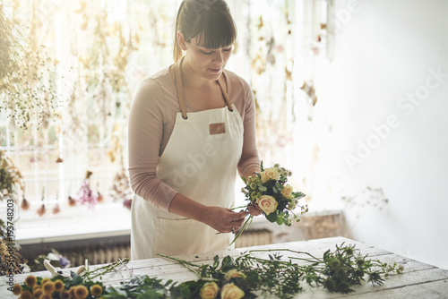 Принти на полотні Female florist arranging flowers at a table in her shop