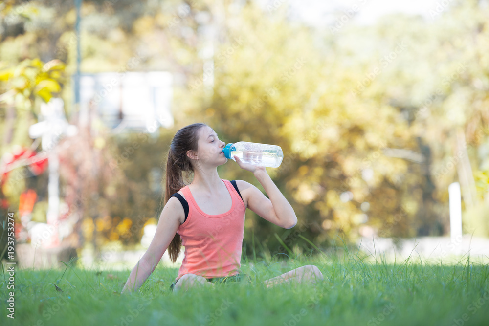 Beautiful young sportswoman drink water at the park After practicing yoga done. Health and Fitness concept Beautiful young sportswoman drink water at the park After practicing yoga done. Health and Fitness concept