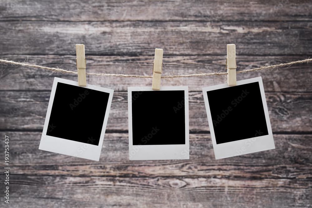 photos hang on a rough rope, fixed with wooden clothespins on a wooden background. photos hang on a rough rope, fixed with wooden clothespins on a wooden background.