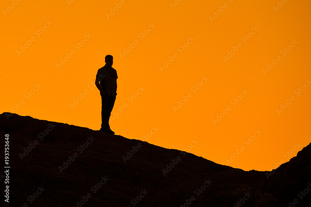 Silhouette of man on a rock watching the sunset
