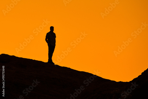 Silhouette of man on a rock watching the sunset