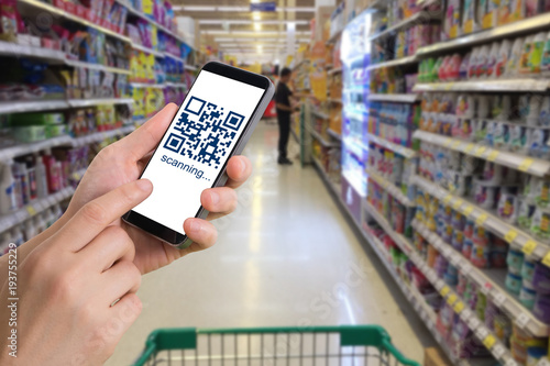 human hand hold and touch smart phone, tablet, cellphone with QR Code number on products shelf store background. concept of shopping online.