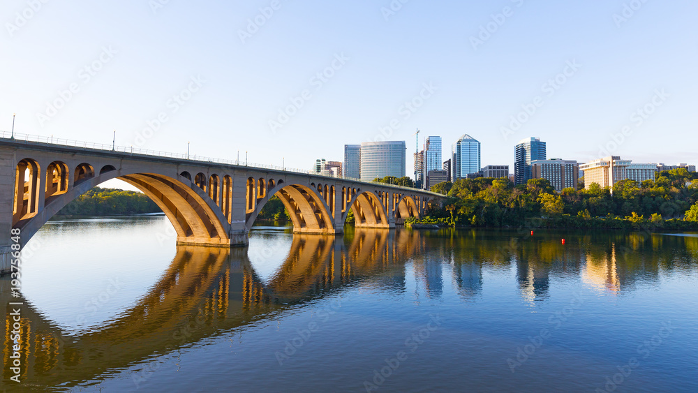 Key Bridge over Potomac River with urban skyscrapers on early morning in Washington DC, USA. A view on the bridge and city development from Georgetown Park neighborhood of US capital.