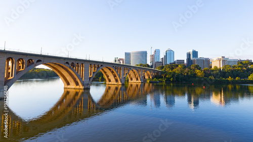 Key Bridge over Potomac River with urban skyscrapers on early morning in Washington DC, USA. A view on the bridge and city development from Georgetown Park neighborhood of US capital. © avmedved