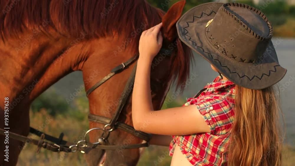 Portrait of a young girl next to the horse on the background of a small lake and forest in summer at sunset. Portrait of a young girl next to the horse on the background of a small lake and forest in summer at sunset.