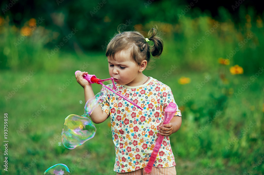 Little girl playing with soap bubbles in the Park Little girl playing with soap bubbles in the Park