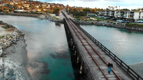 Man walking on train bridge over water