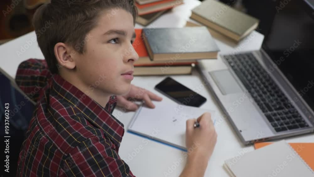 Child reluctantly doing homework under close attention of strict parents Child reluctantly doing homework under close attention of strict parents