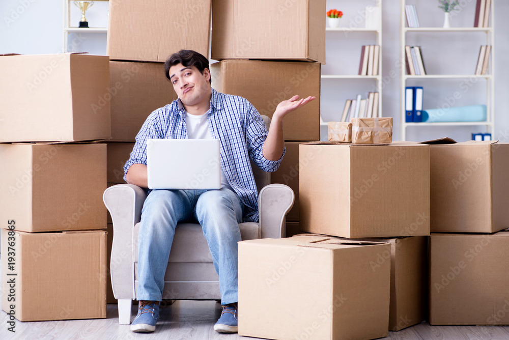 Young man moving in to new house with boxes Young man moving in to new house with boxes