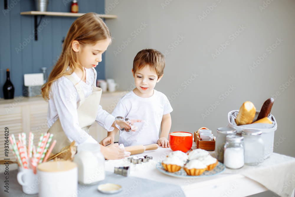 Happy family sister and brother baking cookies in the kitchen Happy family sister and brother baking cookies in the kitchen