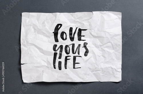 Love your life. Handwritten text on white crumpled paper. Inspirational quote.